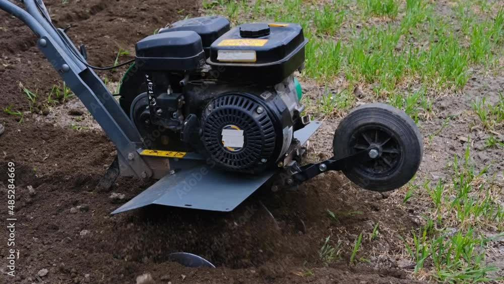 Elderly man plows the soil with a cultivator or tillerblock. Elderly man plows the soil with a cultivator or tillerblock.