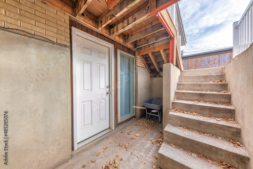 Basement white front door with scattered dry leaves on a concrete stairs