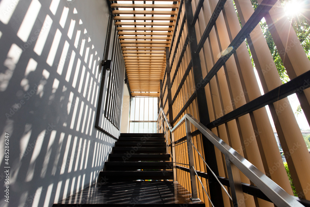Obraz premium Steel and wood stairs are on the side of the building walls.