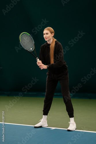 Beautiful lady and athlete with a racket in black sports dress on the tennis court. Fashion and sport concept. © Евгений Гвоздев