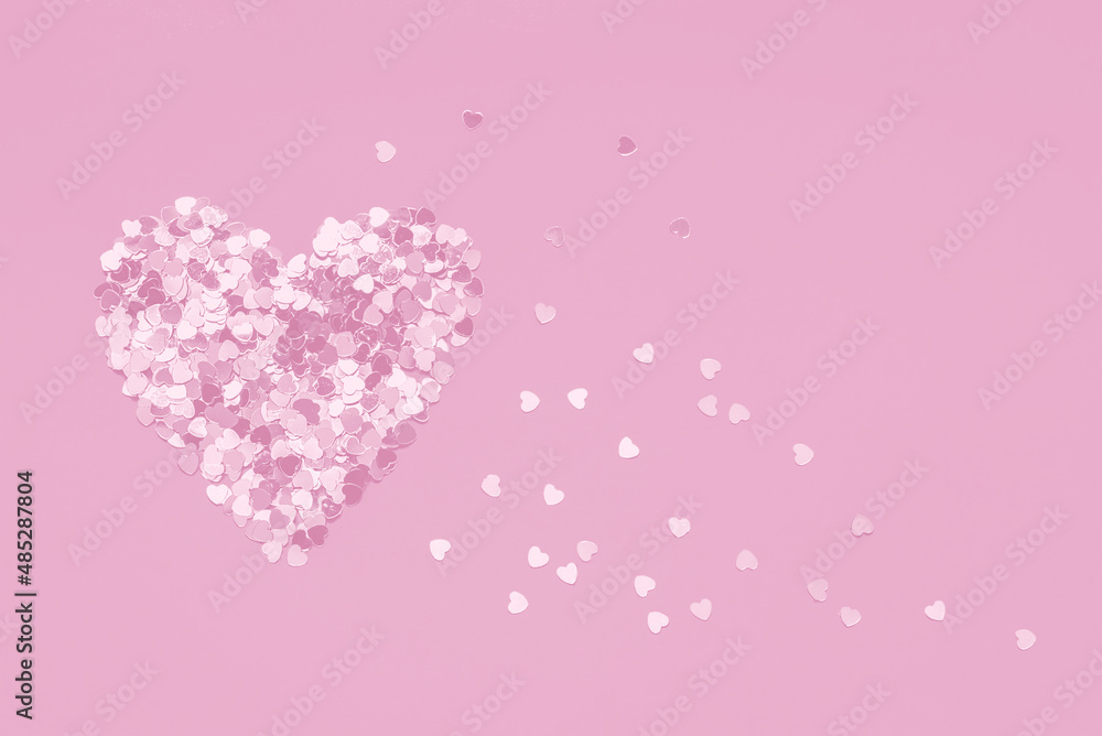 Pink Valentine's Day heart shape made of confetti on pink background. Monochrome style