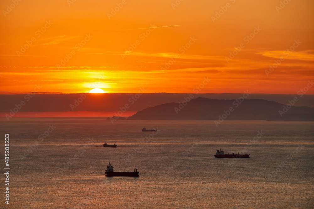 Cargo ships waiting to enter the port of Bilbao with a beautiful sunset