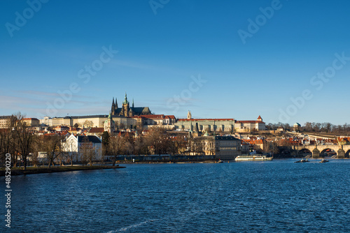 View of Prague Castle and St. Vitus Cathedral with blue sky across the Vltava River with Charles Bridge. High quality photo © Vladimr
