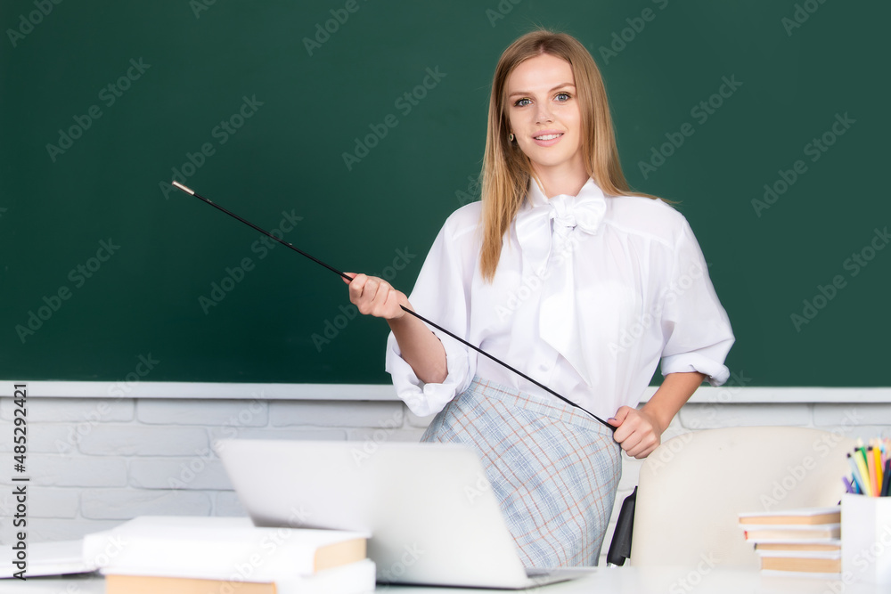 Young sensual teacher pointing on lesson. Cute young woman with pointer teaching near blackboard. Young sensual teacher pointing on lesson. Cute young woman with pointer teaching near blackboard.