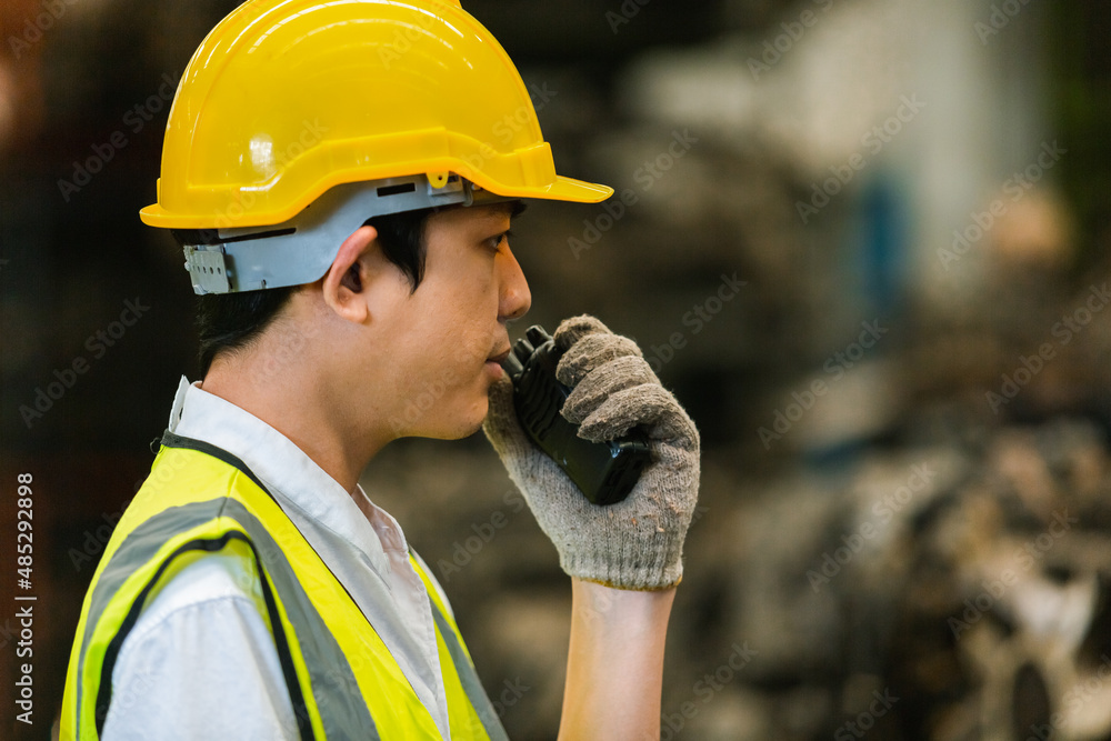 male engineering in uniform holding walkie talkie in warehouse. male worker in factory machinery. workplace heavy industrial. male engineering in uniform holding walkie talkie in warehouse. male worker in factory machinery. workplace heavy industrial.