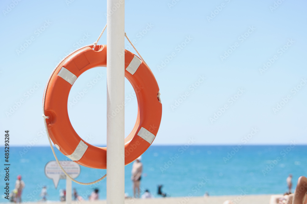 A red lifebuoy hangs on the beach, blurry