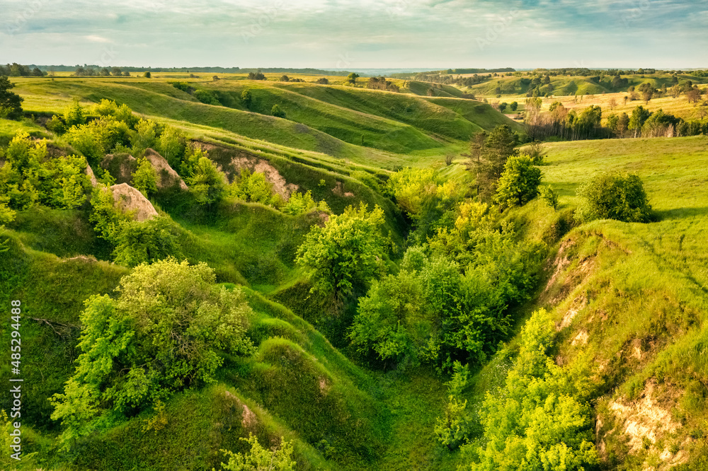 Hills slopes overgrown with green grass, nature reserve Ukrainian Iceland near Vasylkiv, Ukraine. Aerial view
