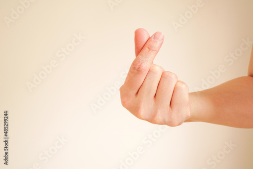 woman hand with mini heart or finger hearts gesture by crisscrossing index finger with thumb , used to convey one's love to their loved ones ,with copy space photo