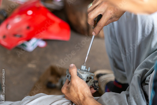 Selective Focus Carburetor Dismantling for rehearsal and cleaning. by a motorcyclist on the side of the road in Thailand