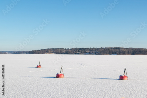 Canvas Print Frozen lake with three red buoys on sunny winter day