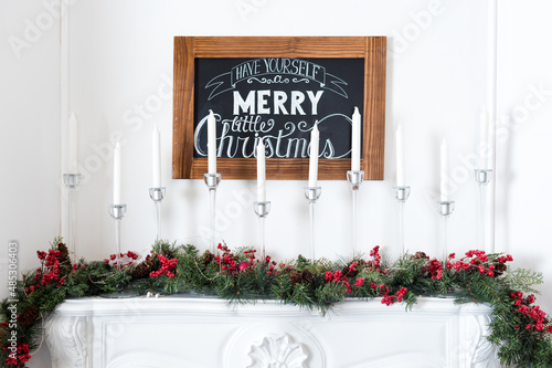 Beautiful Christmas interior. New year decoration. Comfort home. Candles in a metal candlestick on the fireplace.