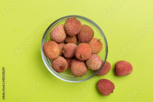 Lychee fruit in bowl on color background. Top view, copy space text
