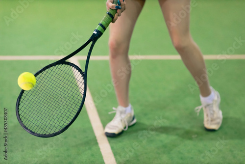 Tennis woman player legs playing training with racket and ball at court.