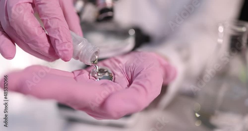 Student pours liquid mercury on gloved hand closeup