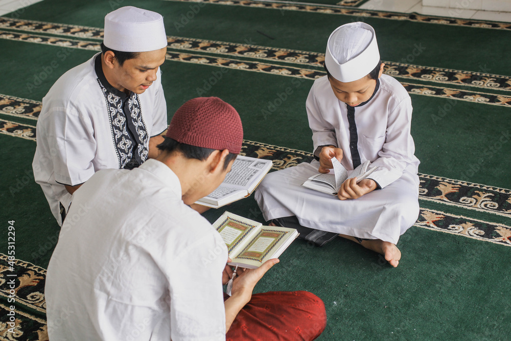 Group of male Muslim teenagers who fill their spare time by taking turns reading the Koran in the mosque