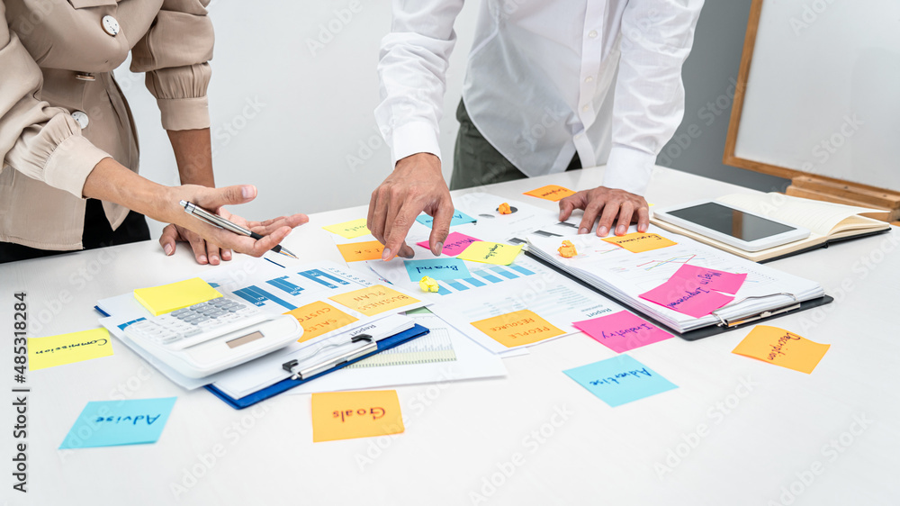 Two business people pointing keyword in post it notes on the table during brainstorming about new business project Two business people pointing keyword in post it notes on the table during brainstorming about new business project