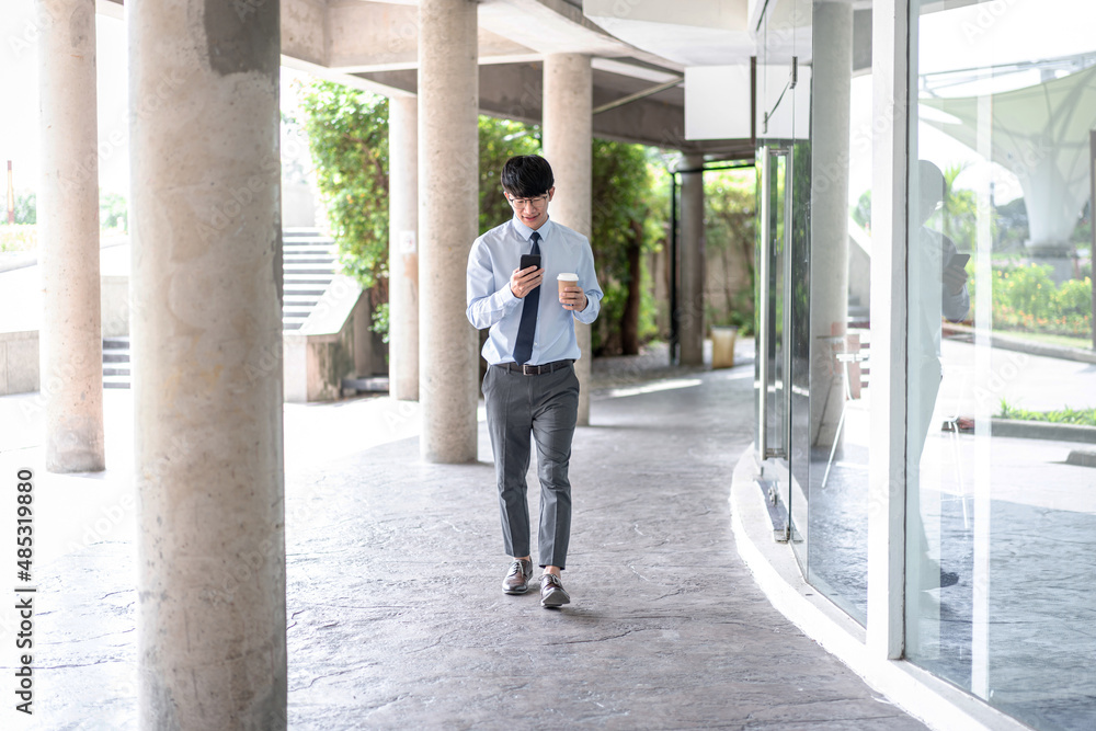 Young business man holding coffee cup and using smartphone to talking business project with partner