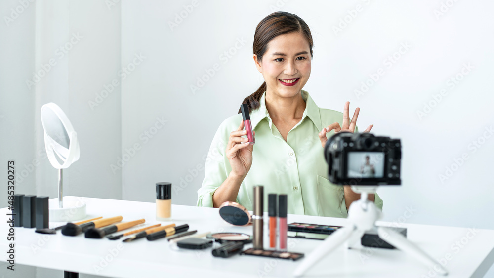 Female beauty blogger is showing lipstick to reviewing product and showing use to makeup cosmetics while recording Female beauty blogger is showing lipstick to reviewing product and showing use to makeup cosmetics while recording