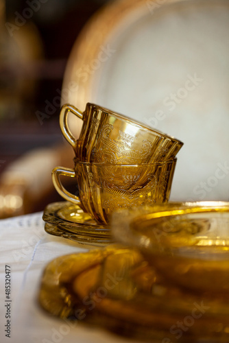 table setting with antique tea glass set with filigree pattern. yellow glass service in the interior. vintage cup close-up