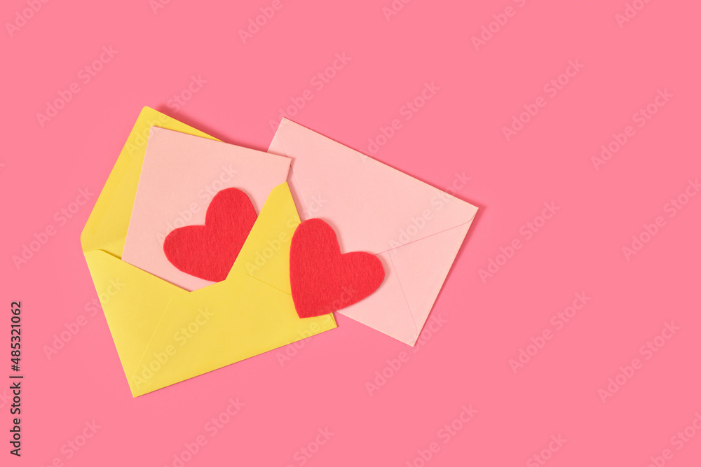 red felt hearts in a bright paper envelope on a pink background