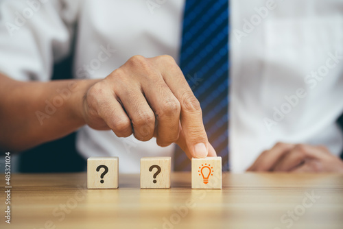 Businessman hands choose idea cube with many questions Mark word a on wood cube.