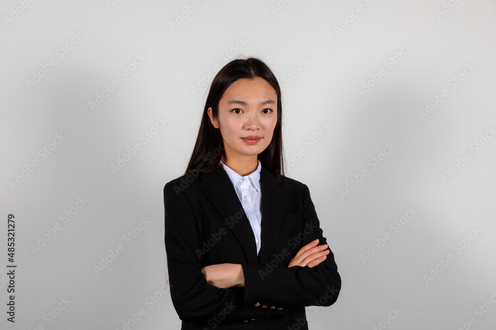 Portrait of a smiling young asian business woman in a black suite crossed hands Portrait of a smiling young asian business woman in a black suite crossed hands