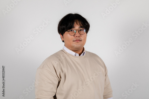 Portrait of a serious chubby young asian man in glasses on a white background © Collab Media