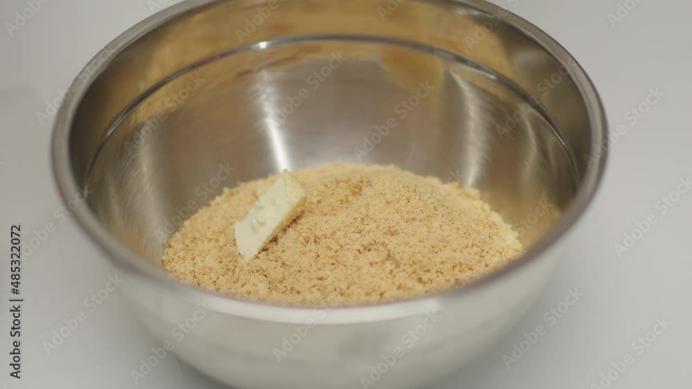 Butter falling down into bowl with ingredients to cook shortbread dough. Cheesecake cooking process in slow motion. Butter falling down into bowl with ingredients to cook shortbread dough. Cheesecake cooking process in slow motion.