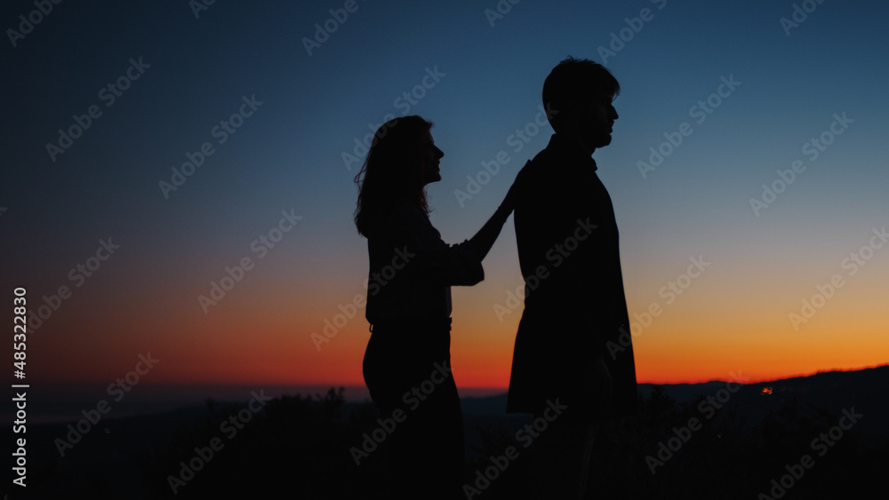 Silhouette of boy and girl hug each other at sunset