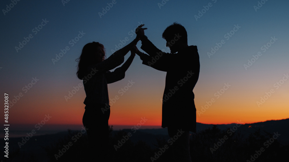 Silhouette of boy and girl are held in hands 