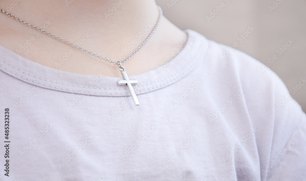 Christian faith. A silver cross on a woman's neck. Pray for forgiveness and believe in goodness. The concept of faith, spirituality and religion. Christian faith. A silver cross on a woman's neck. Pray for forgiveness and believe in goodness. The concept of faith, spirituality and religion.