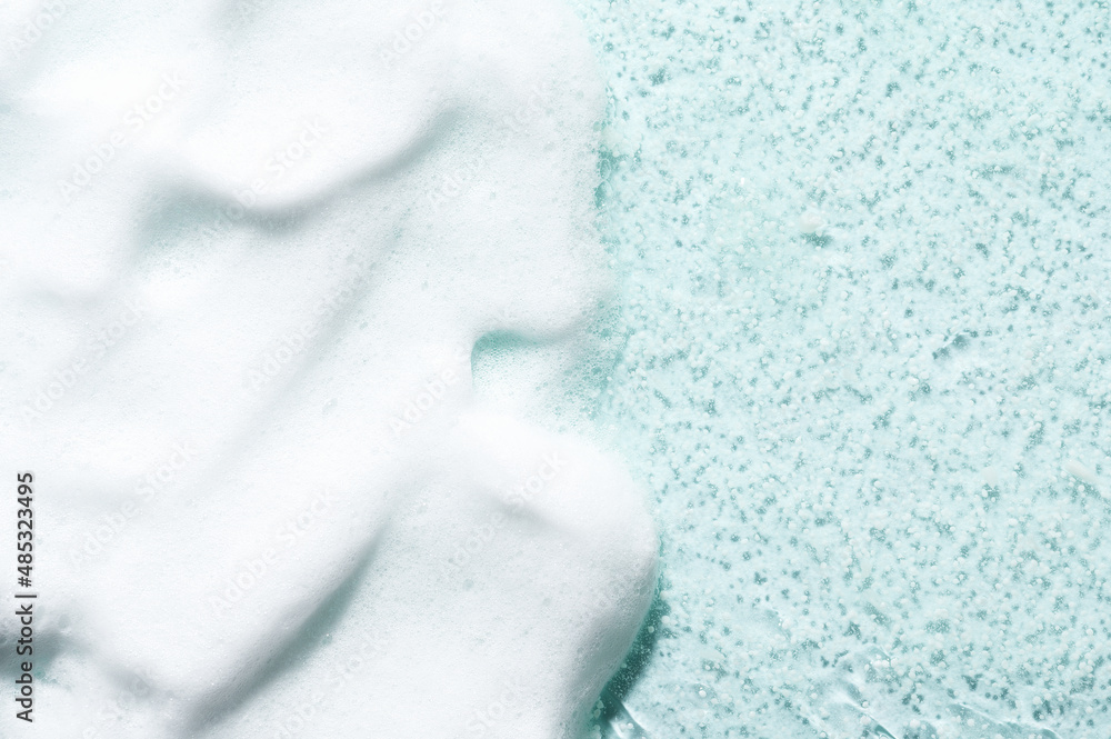 Gentle white foam cleanser cosmetic product for professional skincare on textured turquoise surface close view from above