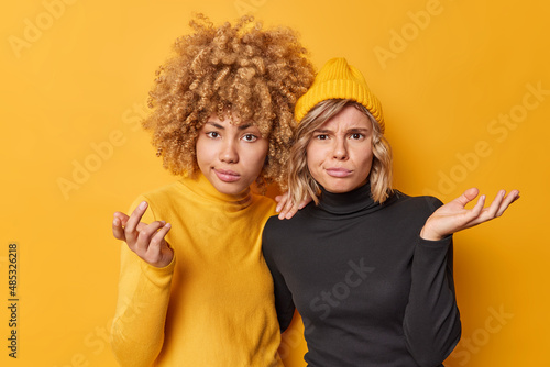 Displeased hesitant women keep palms raised shrug shoulders feel confused look questioned at camera wear casual black and yellow clothes cannot make decision. People and uncertainty concept.