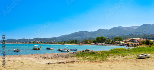 Panorama of Roda tourist town on Corfu island, Greece. Picturesque fishing village on seashore with colorful houses, boats in bay, turquoise water and mountains. Popular tourist destination photo