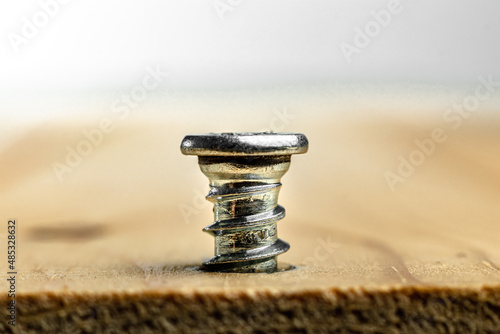 Closeup of screw being screwed into a wooden plank - macro shoot - white background.