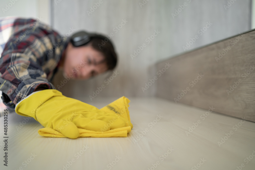 Close up hands in rubber protective yellow gloves cleaning the white surface with a rag. House, housekeeping concept. Close up hands in rubber protective yellow gloves cleaning the white surface with a rag. House, housekeeping concept.