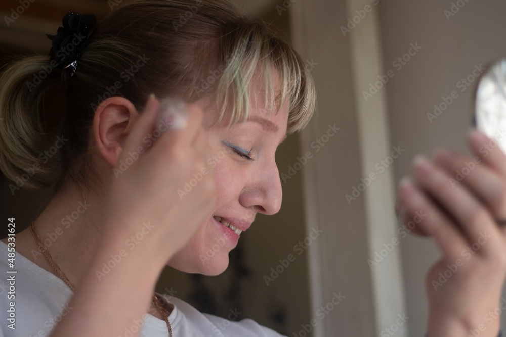 Girl applies powder to her face. Student uses cosmetics. Applying makeup to skin.