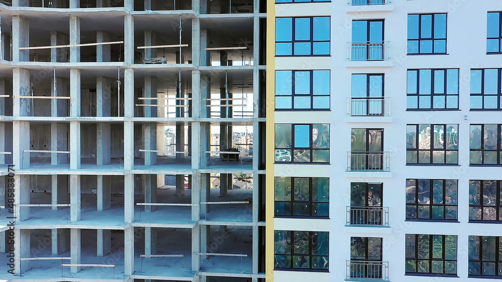 Aerial view of high residential apartment building under construction. Many windows on new apartment building facade under construction. Real estate development. Aerial view of high residential apartment building under construction. Many windows on new apartment building facade under construction. Real estate development.
