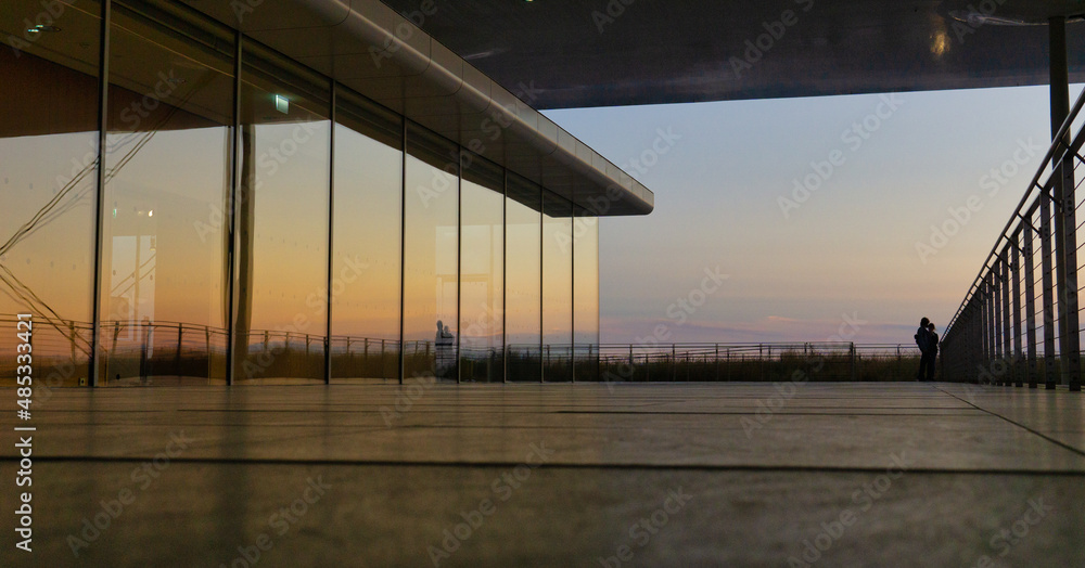 Reflections on a building during dusk with people silhouettes in the background Reflections on a building during dusk with people silhouettes in the background
