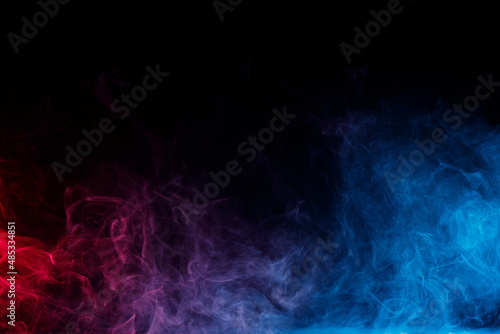 Abstract colored smoke moves on black background. Mystical swirling smoke rolling low across the ground.
