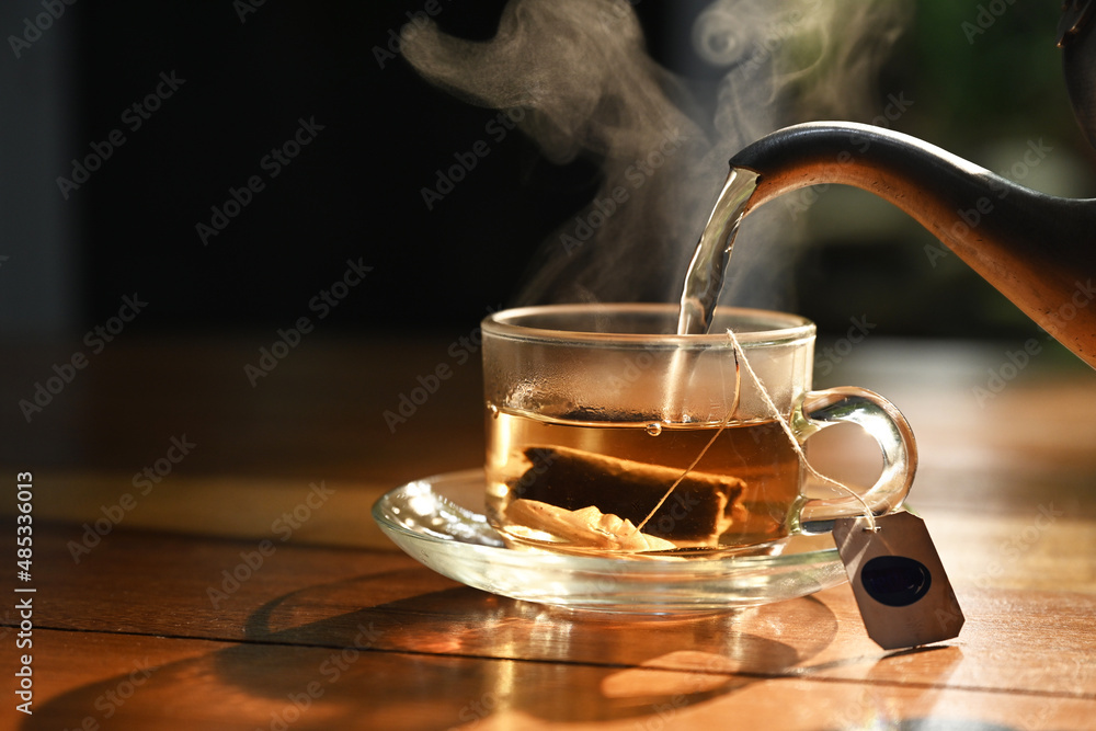 hot water pouring into transparent cup with tea bag - obrazy, fototapety, plakaty 