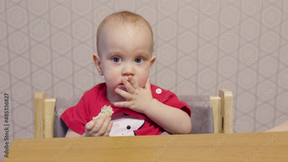 cute baby child making funny face eating cookie with leg on table. portrait eating kid at home kitchen. toddler boy behavior while having breakfast. children healthy nutrition concept. happy caucasian cute baby child making funny face eating cookie with leg on table. portrait eating kid at home kitchen. toddler boy behavior while having breakfast. children healthy nutrition concept. happy caucasian