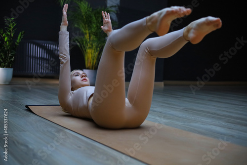 Принти на полотні Full length sporty gymnast woman in white sportswear doing split on mat, spreading legs and bending to touch toe, stretching exercises