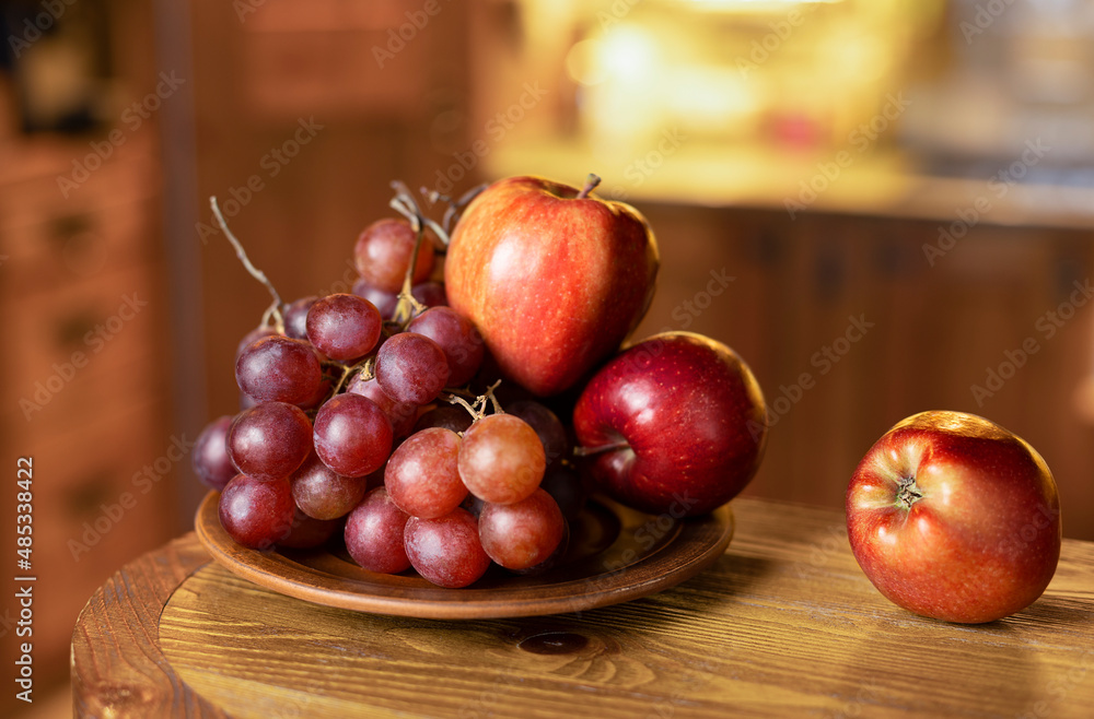Fruit plate with grapes and red apples on a rustic clay plate. Selective focus. Fruit plate with grapes and red apples on a rustic clay plate. Selective focus.