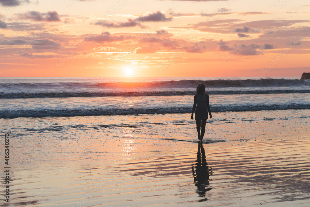 Woman walking on the beach at a beautiful sunset in Costa Rica Woman walking on the beach at a beautiful sunset in Costa Rica