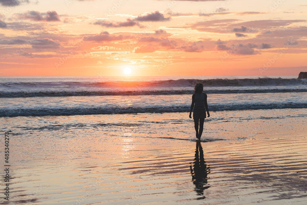 Woman walking on the beach at a beautiful sunset in Costa Rica