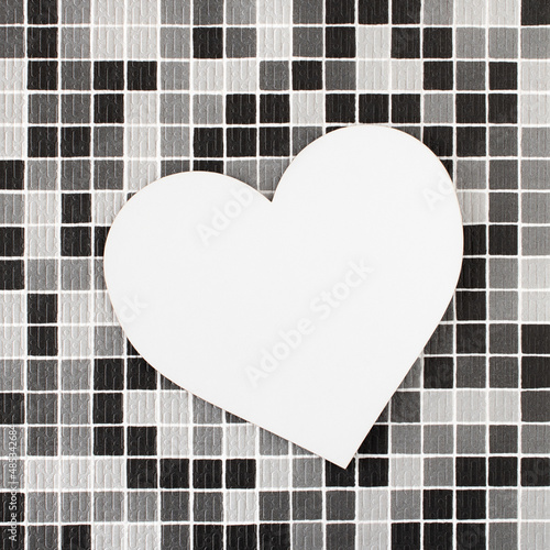 Big white heart on a checkered background of black, white and gray squares. Minimal concept of Valentine's Day. Empty space