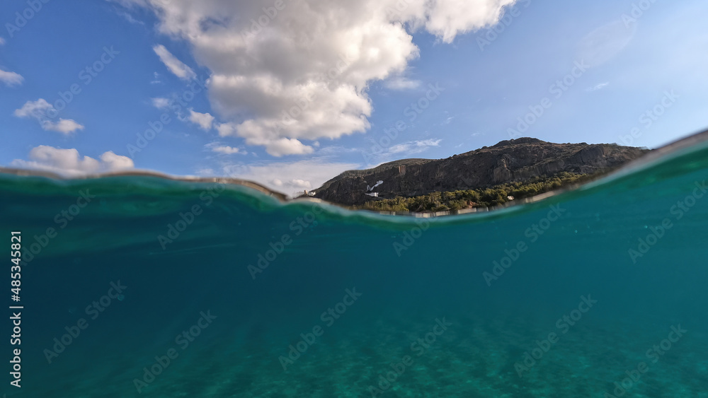 Underwater split photo taken from beautiful emerald bay and beach of Kapsali and famous Monastery of Saint John at the background, Kythira island, Ionian, Greece