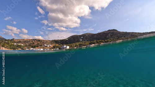Underwater split photo taken from beautiful emerald bay and beach of Kapsali and famous Monastery of Saint John at the background, Kythira island, Ionian, Greece © aerial-drone
