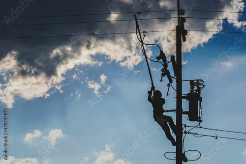The silhouette of power lineman replacing a transformer and hotline clamp, bail  clamp. Using clamp stick grip all type, wearing personal protective equipmen,